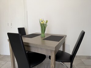 A dining table with four black chairs, a vase with yellow flowers, and a wooden table with a black placemat. - Casa Nina - In downtown Pontedassio, 5 minutes from Imperia, by HOST4U (Pontedassio)