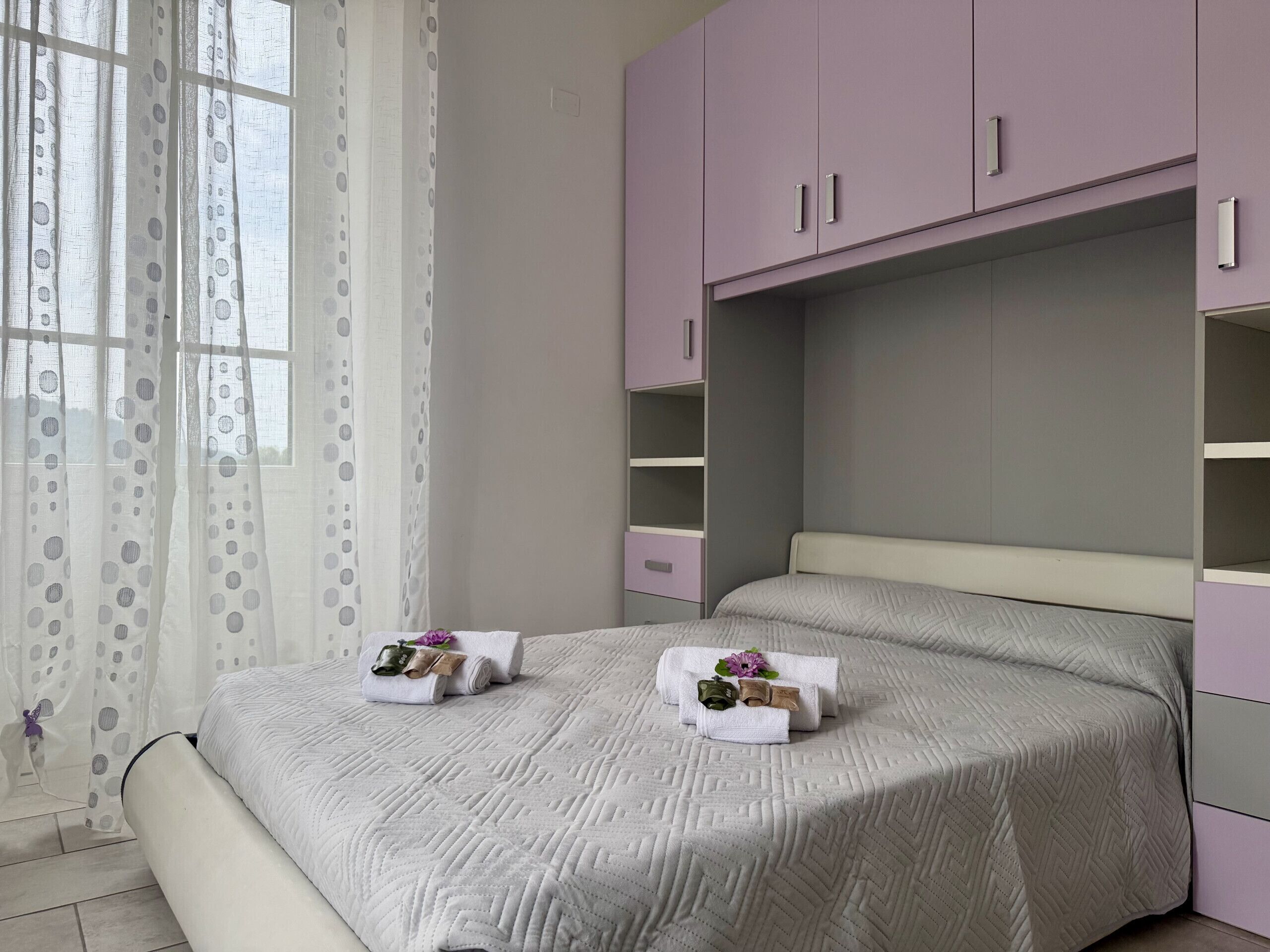 Una camera da letto con un letto, una finestra con tende e un armadio.