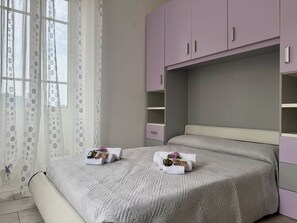 A bedroom with a bed, a window with curtains, and a wardrobe. - Casa Nina - In downtown Pontedassio, 5 minutes from Imperia, by HOST4U (Pontedassio)