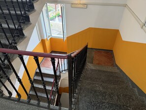 A staircase with a red handrail, black balusters, and a yellow and white wall. - Casa Nina - In downtown Pontedassio, 5 minutes from Imperia, by HOST4U (Pontedassio)