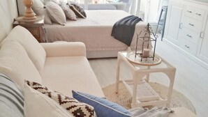 Een gezellige slaapkamer met een bed, een bank, een klein tafeltje en een raam met gordijnen.