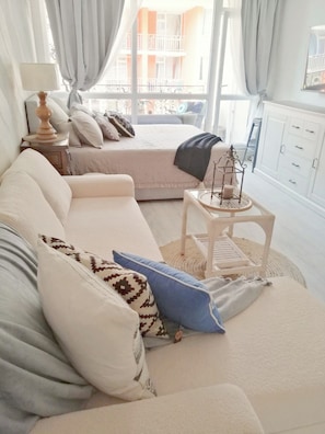 Ein gemütliches Schlafzimmer mit Bett, einer Couch, einem kleinen Tisch und einem Fenster mit Vorhängen.