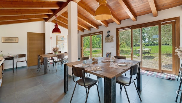 A spacious dining area with a wooden table and chairs, large windows, and a high ceiling with exposed beams. - Apartment 'Iris' with Private Terrace, Wi-Fi and Air Conditioning (Mirano)
