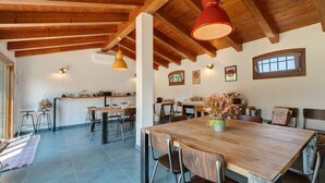 A spacious dining area with a wooden table and chairs, a kitchen in the background, and a high wooden ceiling. - Apartment 'Iris' with Private Terrace, Wi-Fi and Air Conditioning (Mirano)