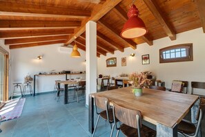 A spacious dining area with a wooden table and chairs, a kitchen in the background, and a high wooden ceiling. - Apartment 'Iris' with Private Terrace, Wi-Fi and Air Conditioning (Mirano)