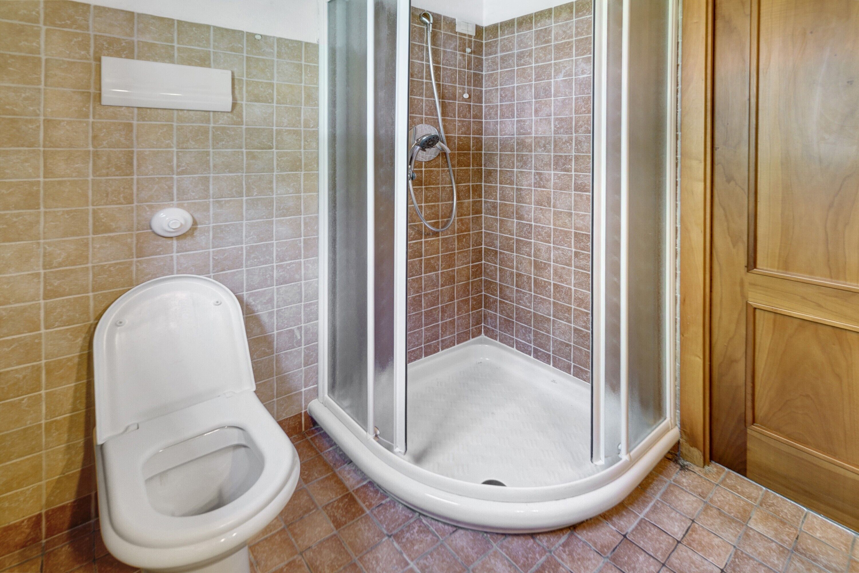 Un bagno con doccia, toilette e pareti piastrellate.