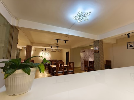 A modern dining area with wooden chairs and tables, a ceiling light fixture, and a 'No Smoking' sign.. Hotel Leggoo