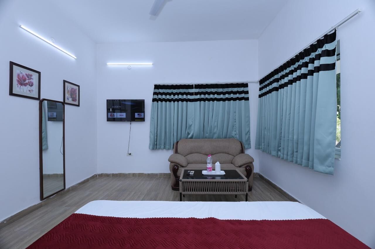 Une pièce comprenant un lit, un canapé, une petite table, un miroir et des rideaux.