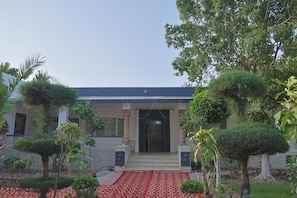 A building with a covered entrance, steps leading up to it, and a red patterned carpet. - Ananda Farm (Rewari)
