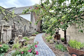 A narrow stone pathway leading to a rustic stone building with a garden. - Holiday home with 2 bedrooms (Kottenheim)