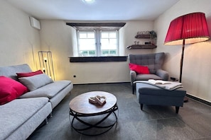 A living room with a grey sofa, a grey armchair, a round coffee table, a red lamp, and a window with a view. - Holiday home with 2 bedrooms (Kottenheim)