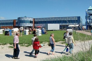 Een gebouw met een moderne glazen gevel, een parkeerplaats en een grasveld.