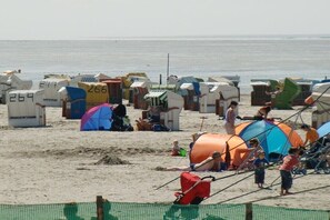 A beach with numerous colorful beach huts and a sandy area. - Holiday apartment with 2 bedrooms (Norddeich)