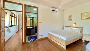 Ein Schlafzimmer mit einem hölzernen Bett, einer Klimaanlage, einer Nachttischlampe und einem Badezimmer mit gefliestem Boden und einem Spiegel.