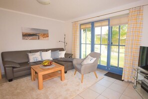 Ein Wohnzimmer mit Sofa, Sesseln, Couchtisch und Fernseher.