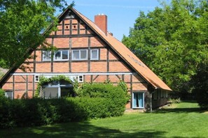 Ein traditionelles Fachwerkhäuschen mit Satteldach, Backsteinschornstein und gepflegtem Rasen.
