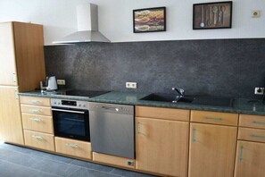 Une cuisine moderne avec des meubles en bois, un lave-vaisselle, une cuisinière et un évier.