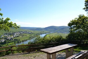 Un belvédère offrant une vue panoramique, avec un banc en bois, une rivière et une ville située dans la vallée en contrebas.