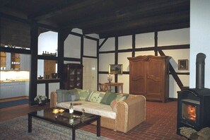 Ein gemütliches Zimmer mit einer Couch, einem Tisch, einem Kamin und einer Küchenzeile.