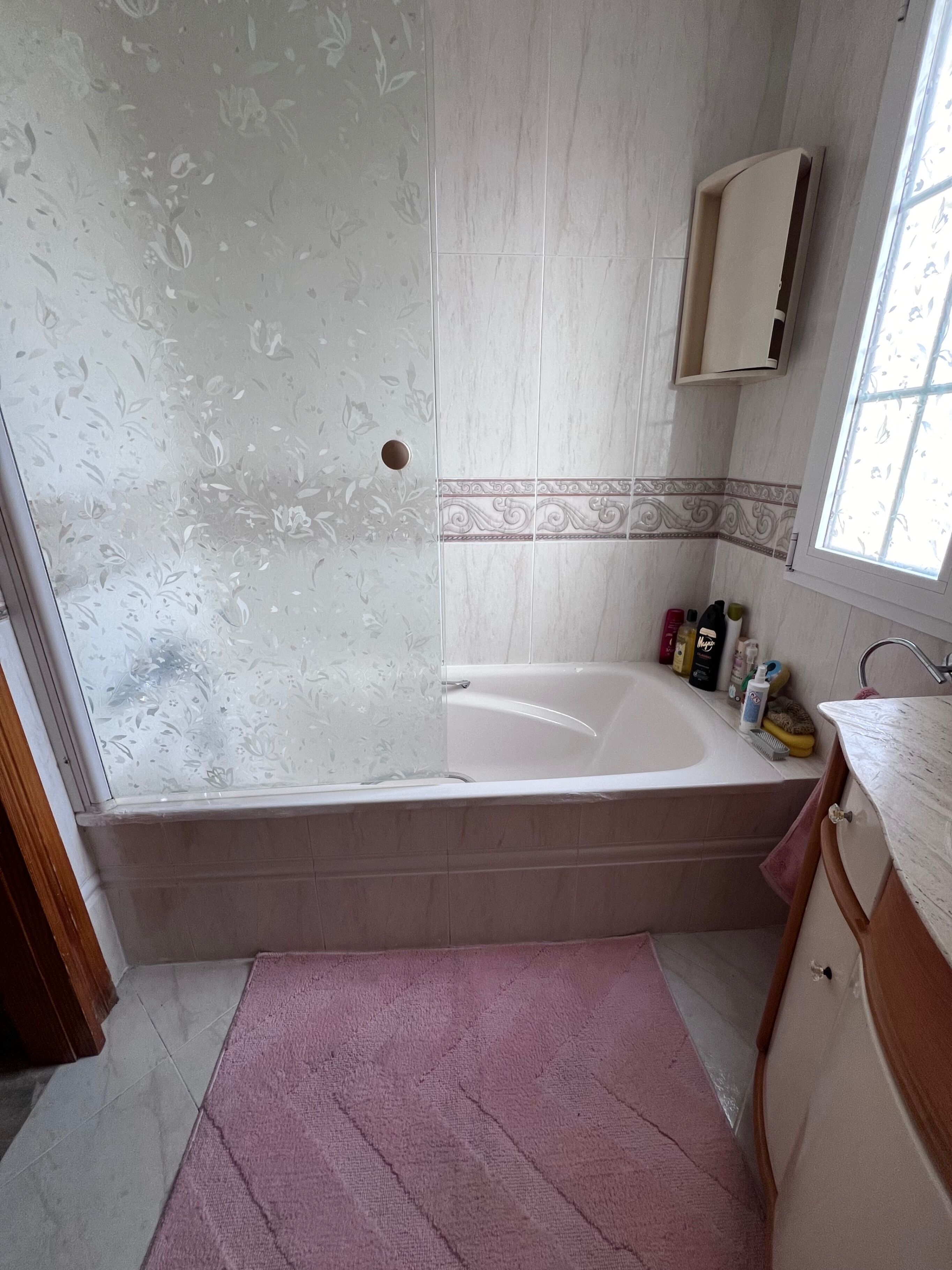 Ein Badezimmer mit Badewanne, Fenster, Waschbecken und Spiegel.