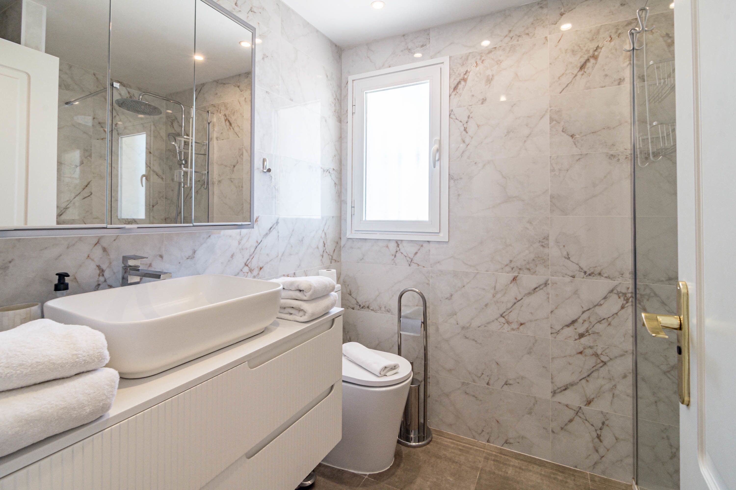 A bathroom with a large sink, mirror, and a shower area.