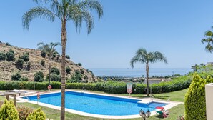 A swimming pool with a view of the sea, surrounded by palm trees and a hilly landscape. - Bv373a - Corner Penthouse With Rooftop Terrace (Mijas)