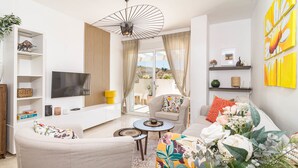 A modern living room with a sofa, armchair, TV, and a dining table. - Bv373a - Corner Penthouse With Rooftop Terrace (Mijas)