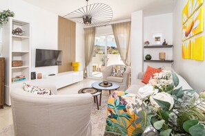Un salon moderne comprenant un canapé, un fauteuil, un téléviseur et une table à manger.