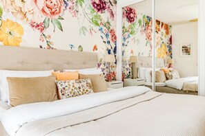 A hotel room with a large bed, a mirror, a nightstand, and a floral wallpaper. - Bv3.73a - Corner Penthouse With Rooftop Terrace (Mijas)
