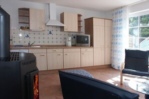 Eine Küche mit Herd, Schränken, einem Fernseher und einem Essbereich mit Tisch und Stühlen.