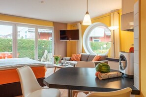 Ein modernes Zimmer mit einem Bett, einem Esstisch, einem Sofa, einem Fernseher und einer Waschmaschine.