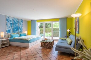 Ein Schlafzimmer mit Bett, Nachttischen, einem Sofa, einer Lampe und Blick nach draußen.