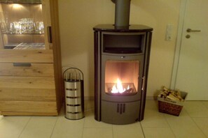 Ein Holzofen mit Glastür, ein Metallbehälter und ein Holzkorb daneben.