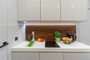 Eine moderne Küche mit weißer Arbeitsplatte, Edelstahlgeräten und einer Holz-Spritzschutzwand.