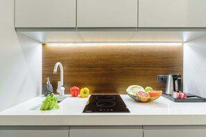 Eine moderne Küche mit integriertem Induktionskochfeld, einer Edelstahl-Spüle und einer Holzrückwand.