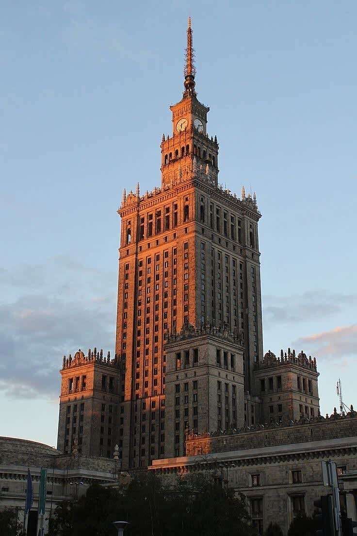 A large, historic building with a prominent clock tower, multiple floors, and a symmetrical facade.