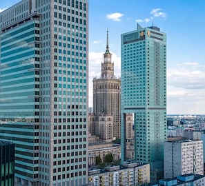 Eine Stadtansicht mit modernen Hochhäusern, einem historischen Turm und blauem Himmel.