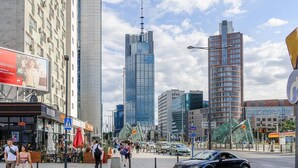 Een stadsstraat met hoge gebouwen, een bushalte en voetgangers.