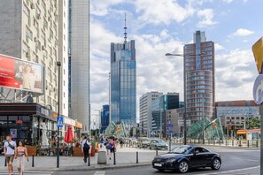 Eine Stadtstraße mit hohen Gebäuden, einer Bushaltestelle und Fußgängern.