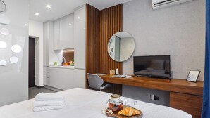 Een moderne hotelkamer met een bed, een bureau met een televisie, een spiegel en een wandairconditioner.