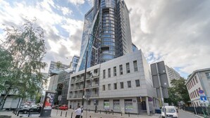 Een modern gebouw met een gebogen glazen gevel, een plat dak en een heldere lucht.
