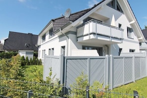 Ein zweigeschossiges Wohngebäude mit Satellitenschüssel, Balkon und geschlossenem Eingangsbereich.