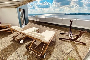 Terraza en la azotea con una silla de descanso, una mesita y vista a un cuerpo de agua.