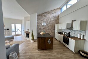 Una cocina moderna con una pared de acento de piedra, una isla de madera y muebles de cocina blancos.