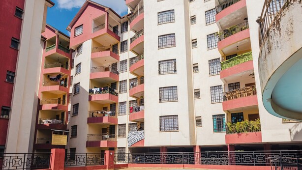 Un edificio a più piani con balconi, una piscina e cielo sereno.