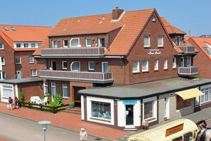 Ein traditionelles Backsteingebäude mit Balkon, einem kleinen Laden und einer Kutsche.