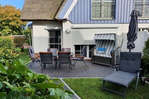 Eine Terrasse mit Gartenmöbeln, einem Grill und einem überdachten Sitzbereich.