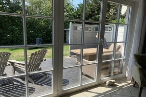 Ein Zimmer mit einer großen Glasschiebetür, die auf eine Terrasse mit Gartenmöbeln führt.