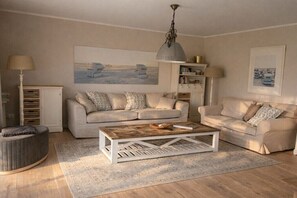 Ein Wohnzimmer mit zwei Sofas, einem Couchtisch, einer Lampe und einem Bücherregal.