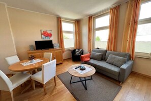 Ein Wohnzimmer mit einer Couch, einem Couchtisch, einem Fernseher und einem Essbereich mit Stühlen und einem Tisch.
